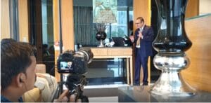 Man giving presentation filmed by cameraman indoors