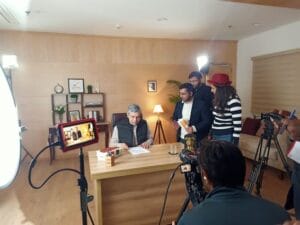Man being filmed at desk by camera crew